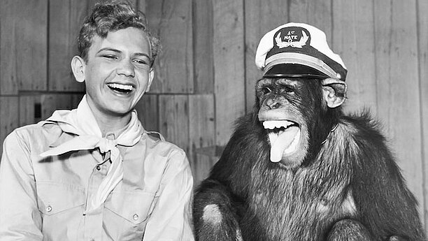 Svartvitbild med en pojke och en chimpans skrattar